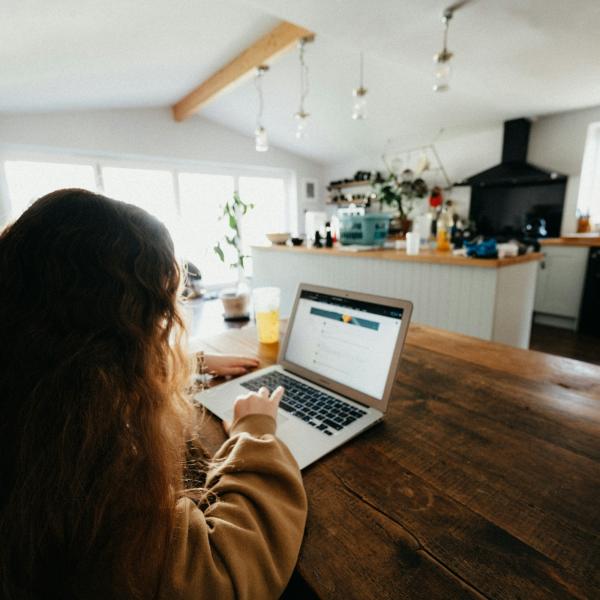 student sitting in kitchen doing homework on a laptop