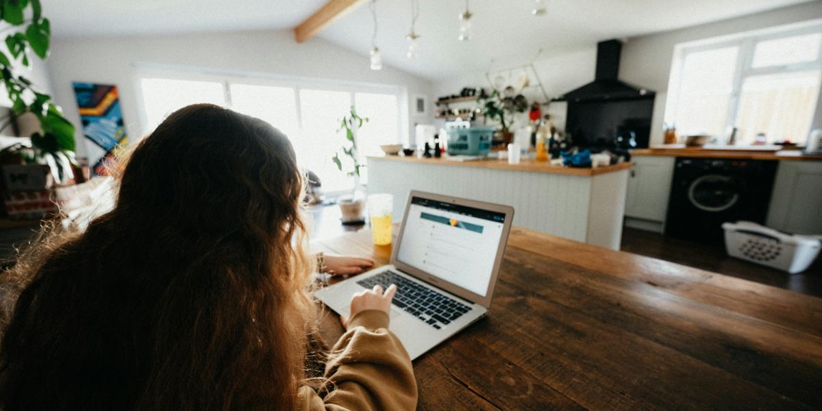 student sitting in kitchen doing homework on a laptop